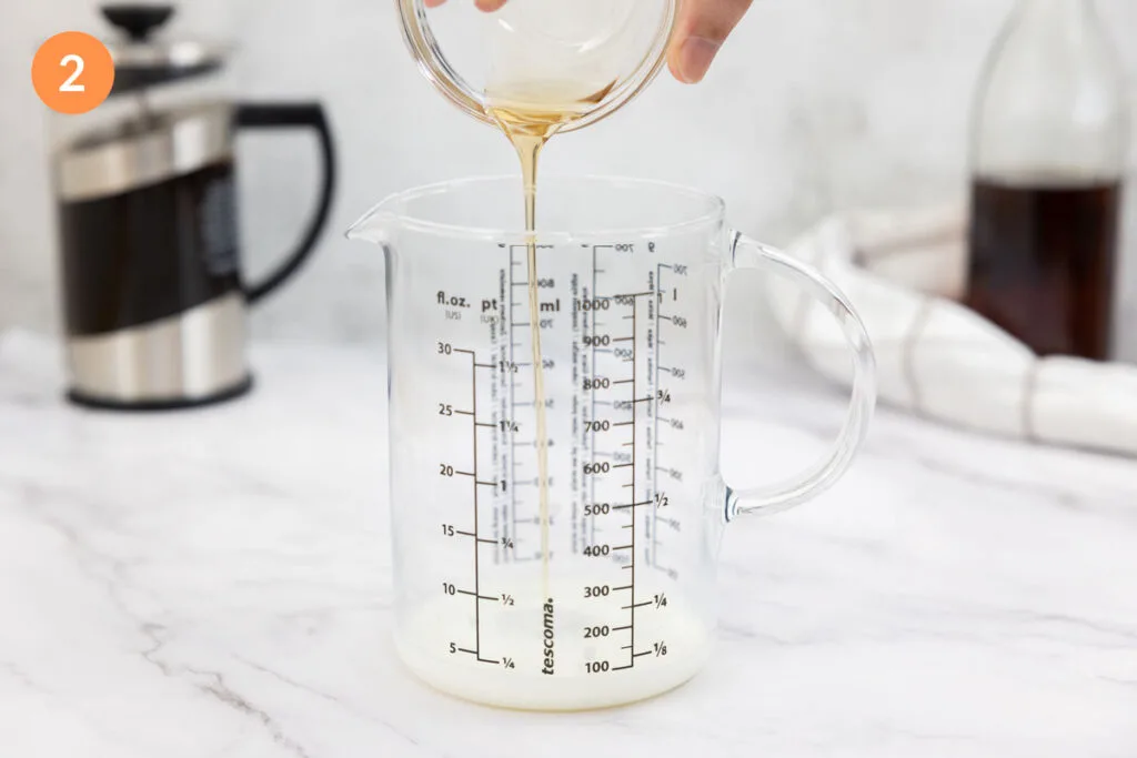 Pouring vanilla syrup into a jug of milk