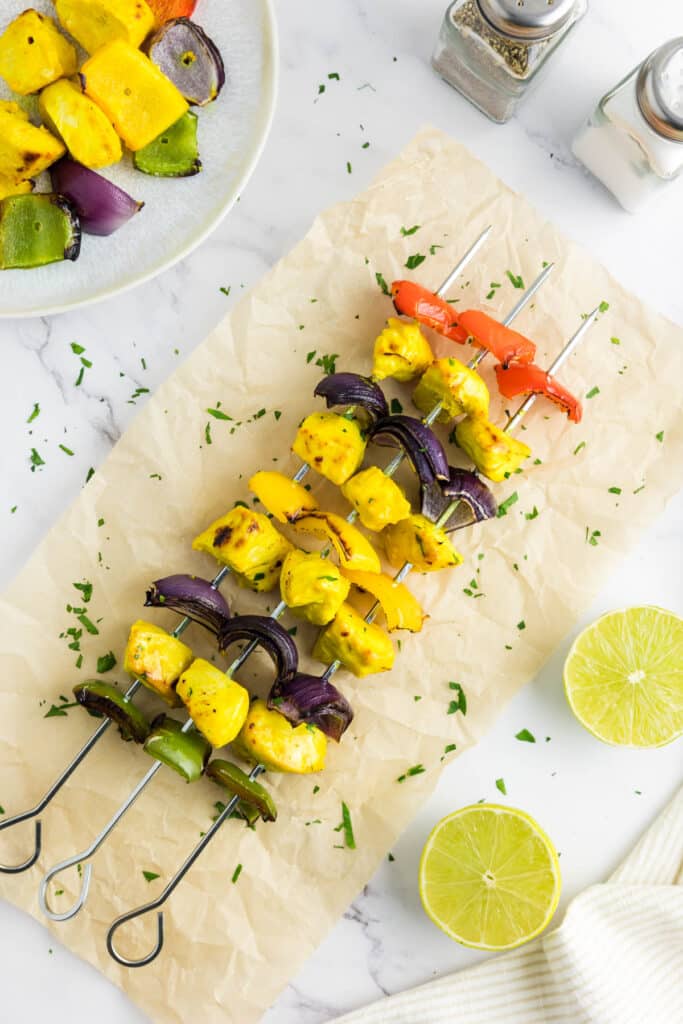 Chicken kabobs on metal skewers next to lime