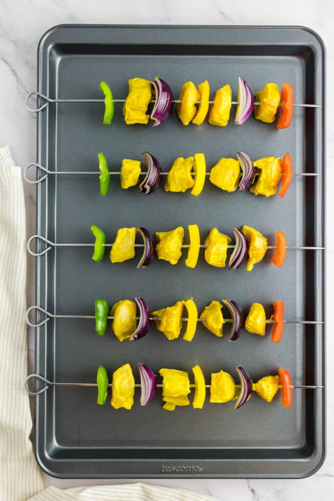 Skewered chicken kabobs on a baking tray