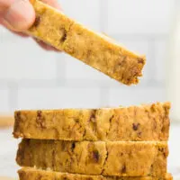 One slice of banana bread being taken from a pile of banana bread slices