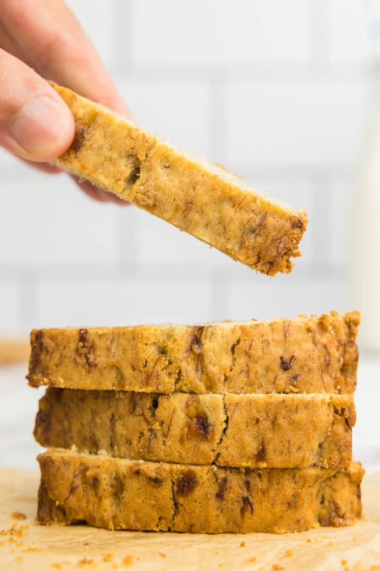One slice of banana bread being taken from a pile of banana bread slices