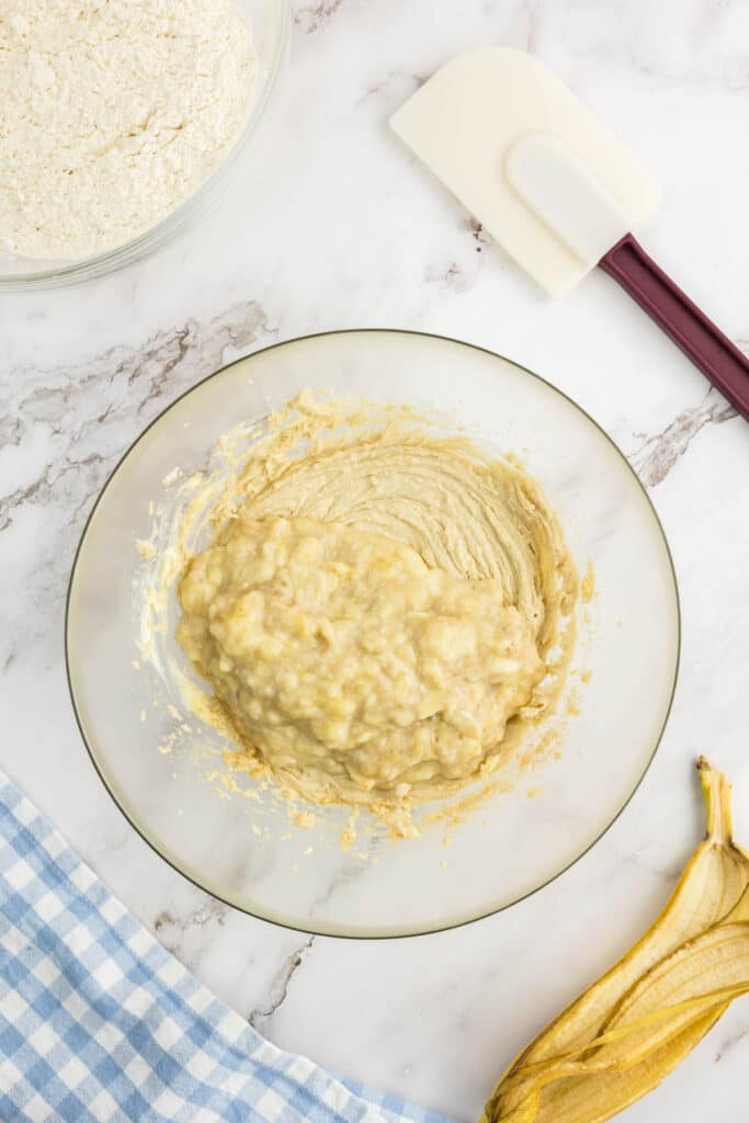 Mashed banana added to creamed butter and sugar in a large bowl