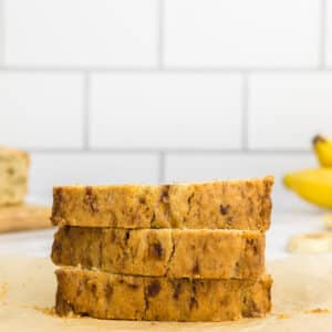 three slices of banana bread which has been made without baking soda with bananas in the background