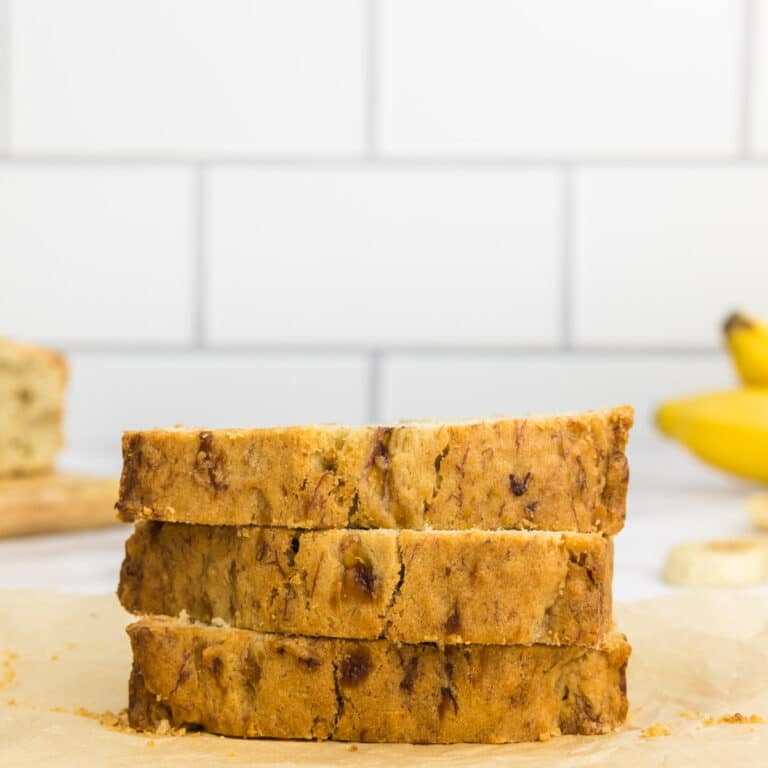 three slices of banana bread which has been made without baking soda with bananas in the background