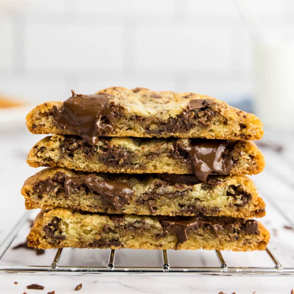 Chocolate chip cookies without brown sugar cut in half on a cooling rack with gooey chocolate