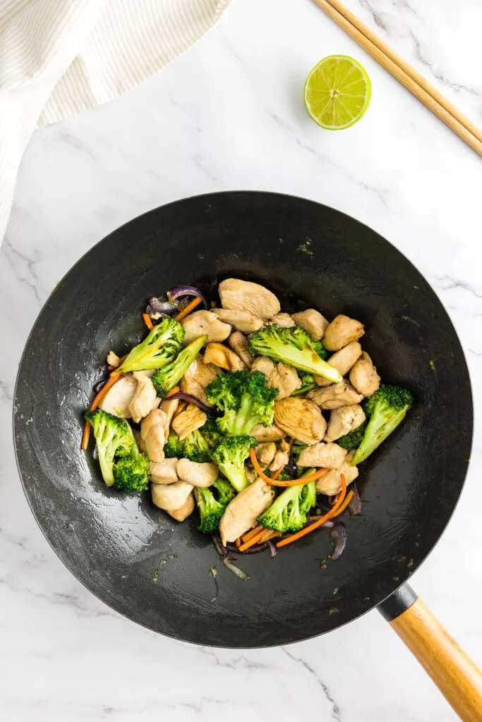 Stir fried chicken added to the stir fried vegetables in a wok