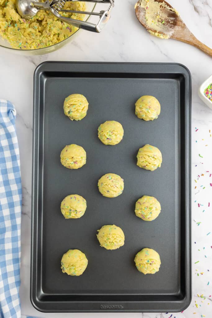 Sprinkled cookie dough balls on a baking tray