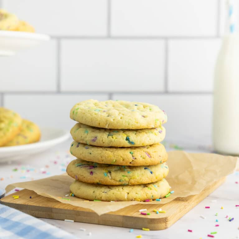 Sprinkle sugar cookies stacked on a wooden board