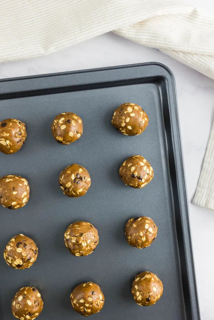 Circular cookie dough balls on a non-stick baking tray
