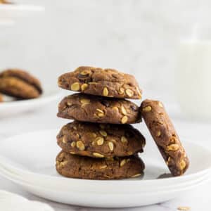 Vegan oatmeal chocolate chip cookies stacked on a white plate