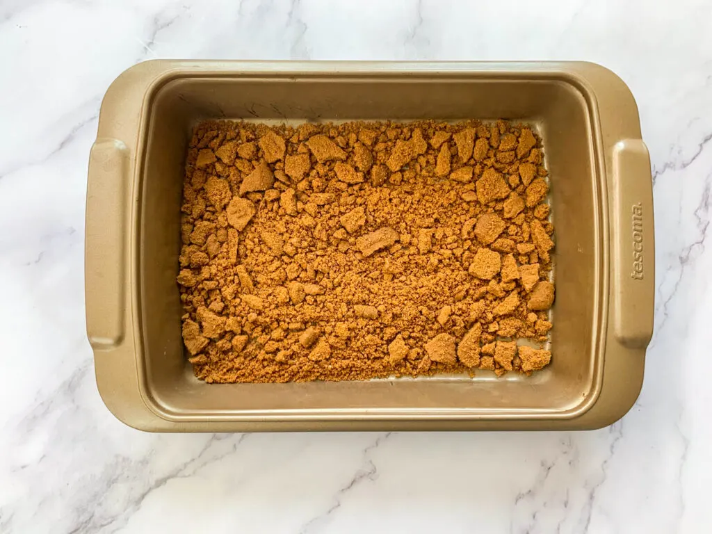 Crushed biscoff biscuits in a baking pan