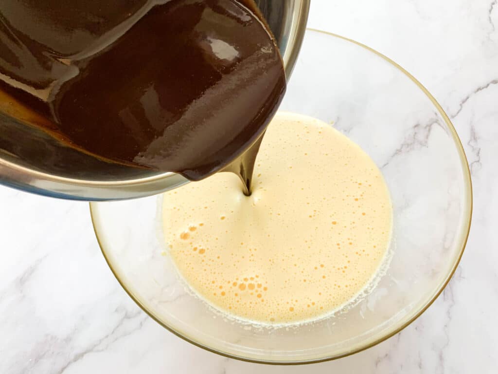 Pouring the chocolate mixtured into the mixed eggs and sugar bowl