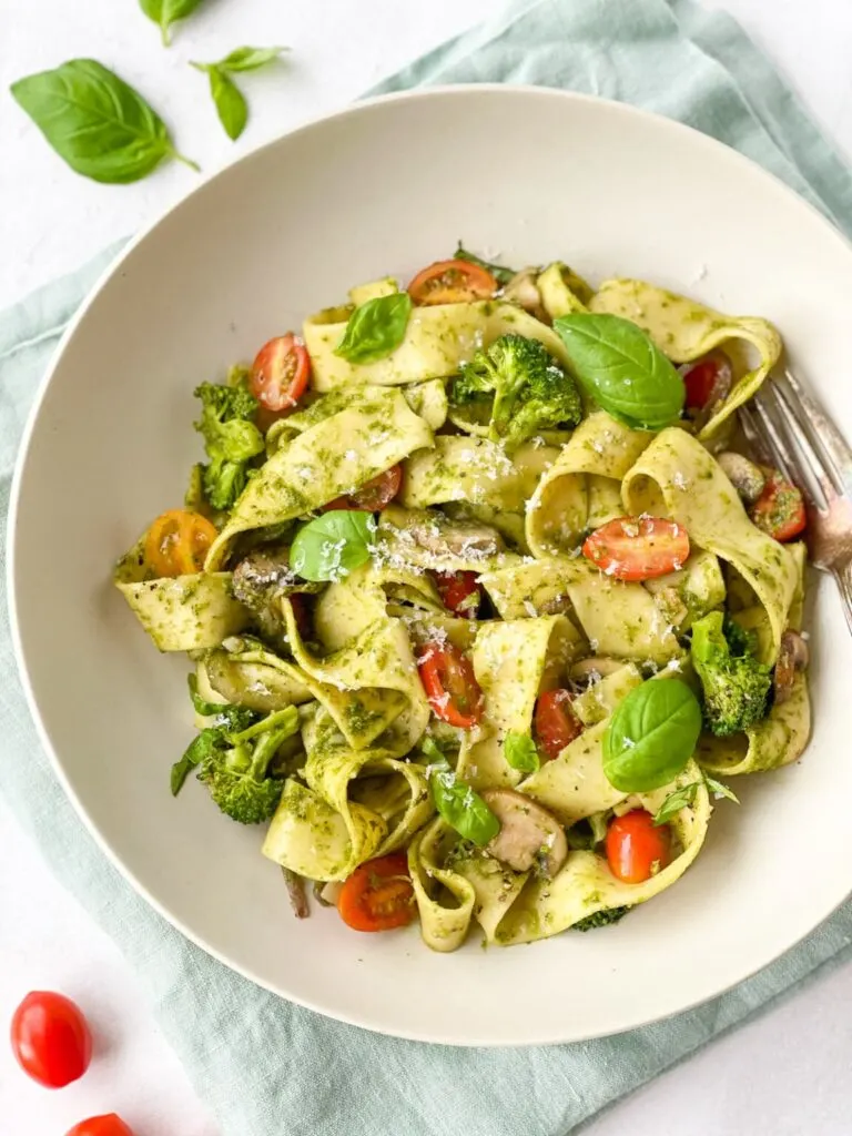 Pappardelle pesto pasta garnished with basil and cherry tomatoes