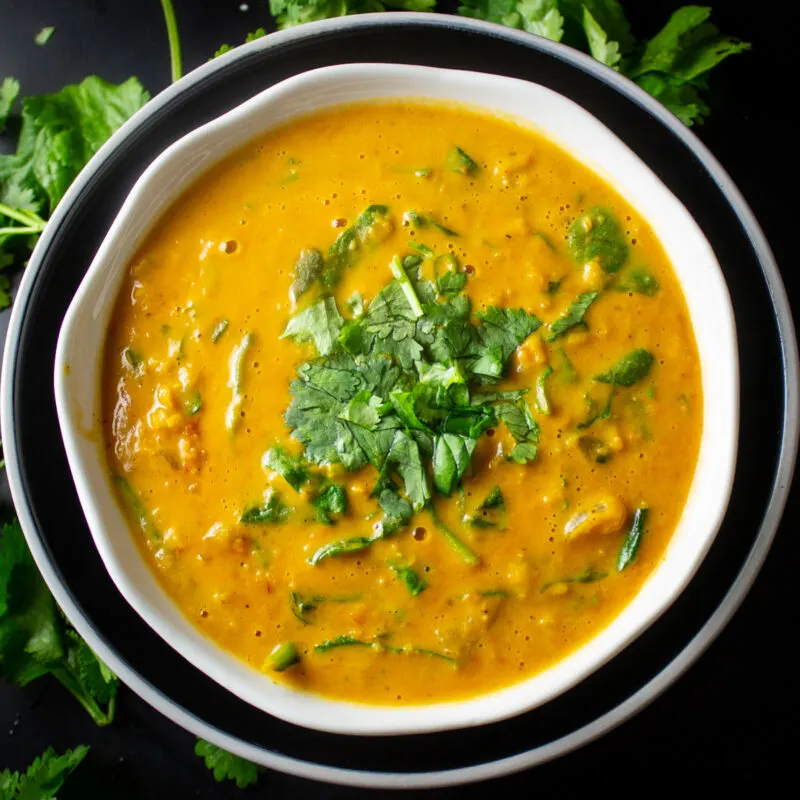 curried lentil soup in a bowl with sliced coriander