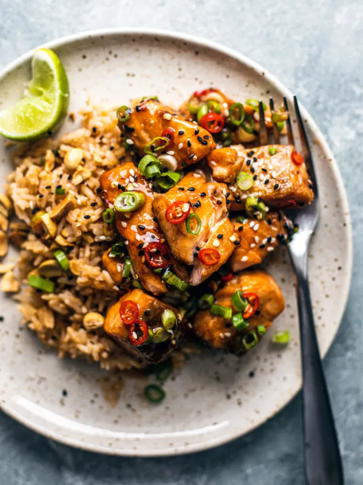 Sweet chili salmon bites on stir fried rice with a garnish of lime