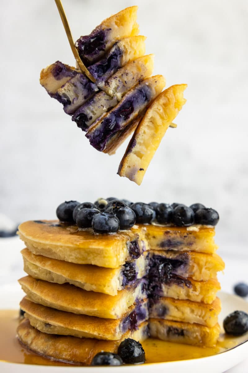 Buttermilk blueberry pancakes with a fork picking a bite sized portion up