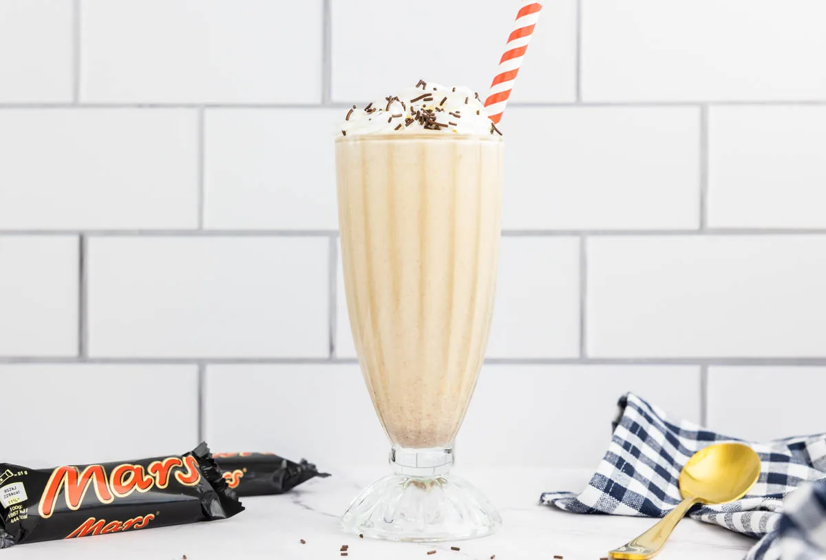 Mars milkshake in a milkshake glass with mars bars in the background
