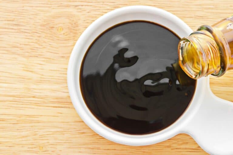 Oyster sauce being poured into a measuring cup.