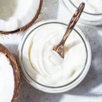 Coconut cream in a bowl next to fresh coconuts.