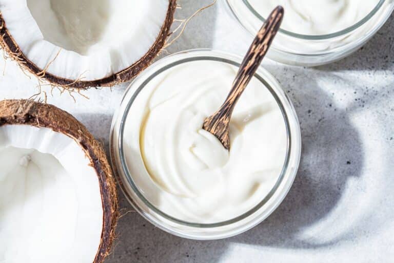 Coconut cream in a bowl next to fresh coconuts.