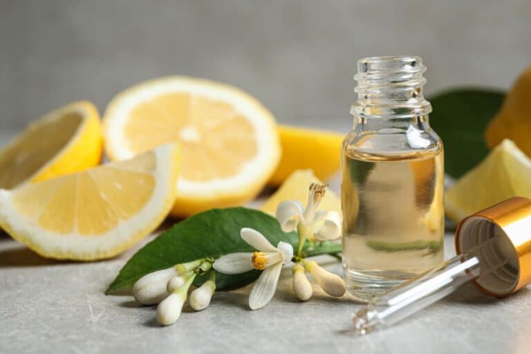 Lemon Extract in a bottle with lemons behind it.
