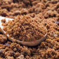 A pile of brown sugar with a wooden spoon.