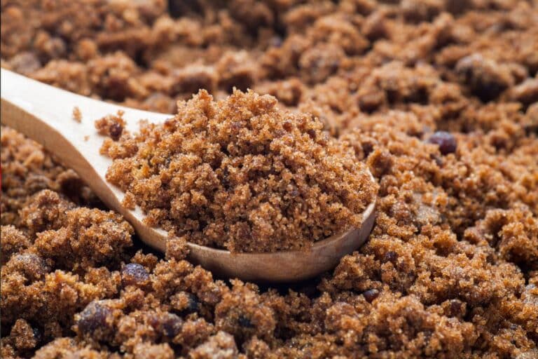 A pile of brown sugar with a wooden spoon.