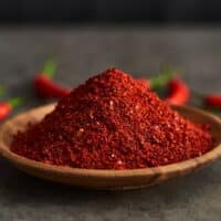 Cayenne peppers on a table and cayenne powder in a bowl.