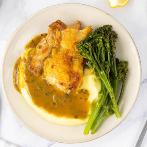Chicken and mashed potatoes served with a pan sauce and tenderstem broccoli.