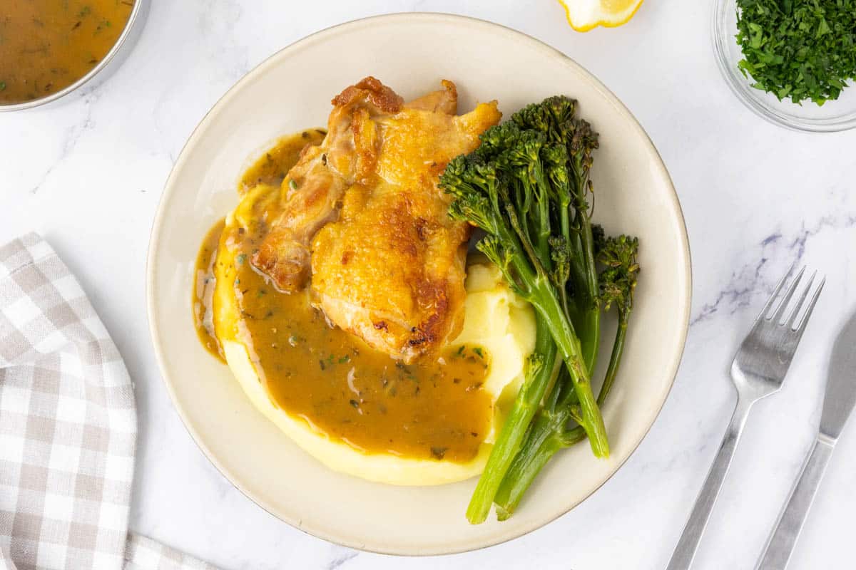Chicken and mashed potatoes served with a pan sauce and tenderstem broccoli.