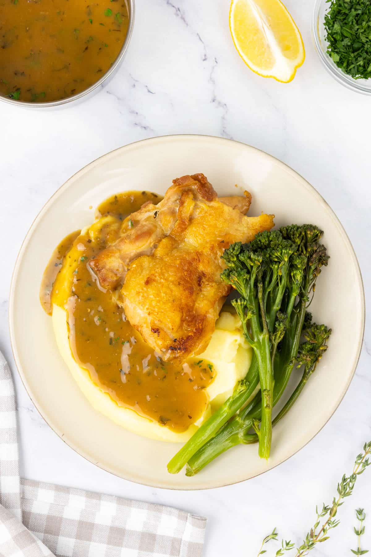 Golden and crispy chicken with creamy mashed potato and a pan sauce on a plate.