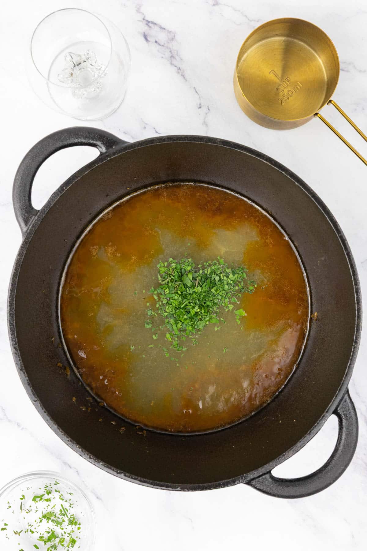 Parsley, thyme and chicken stock reducing in a pan.