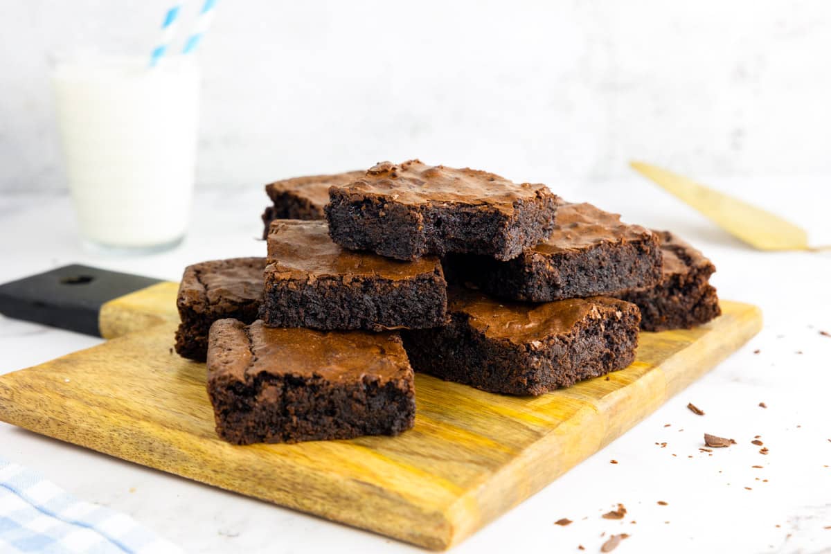 A stack of chocolatey, fudgy brownies on a board.