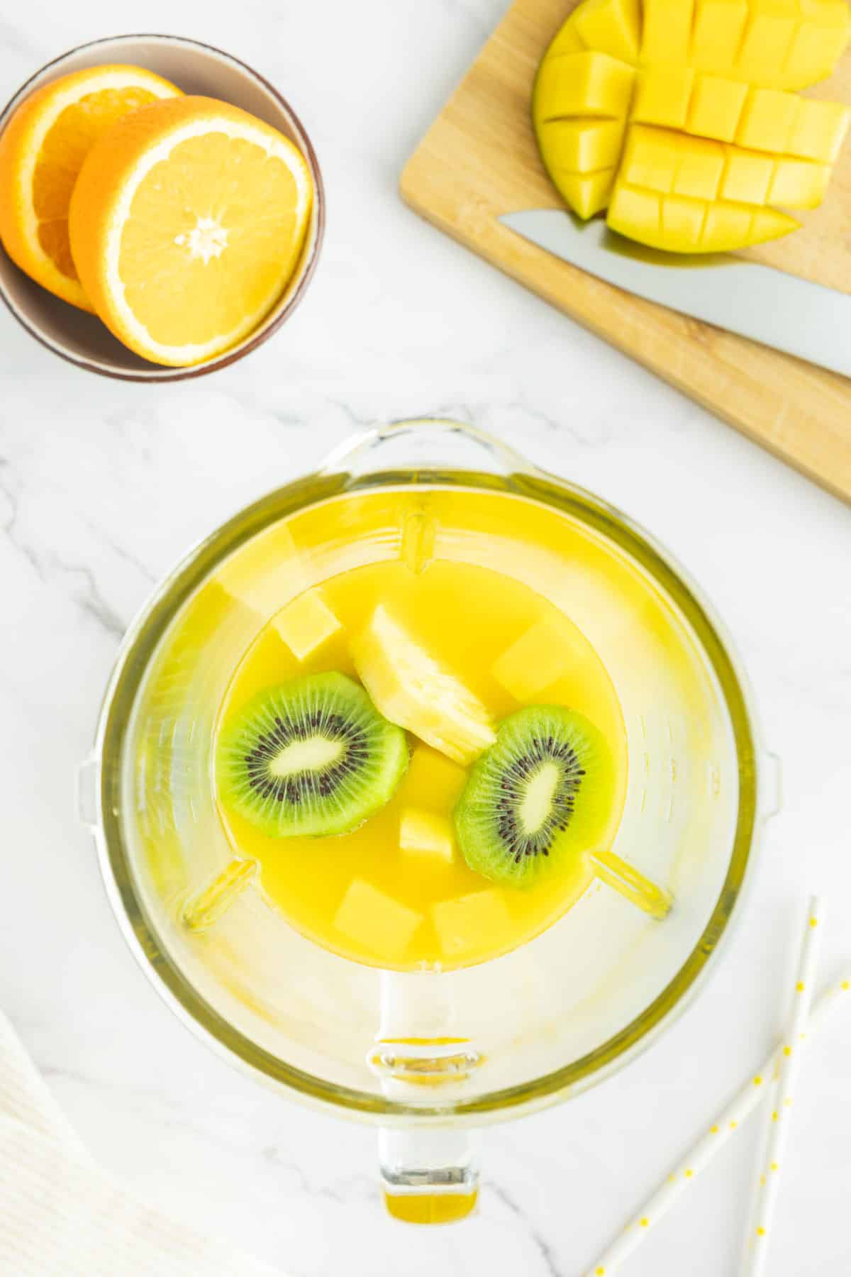 Mango, pineapple, kiwi and orange juice in a blender.