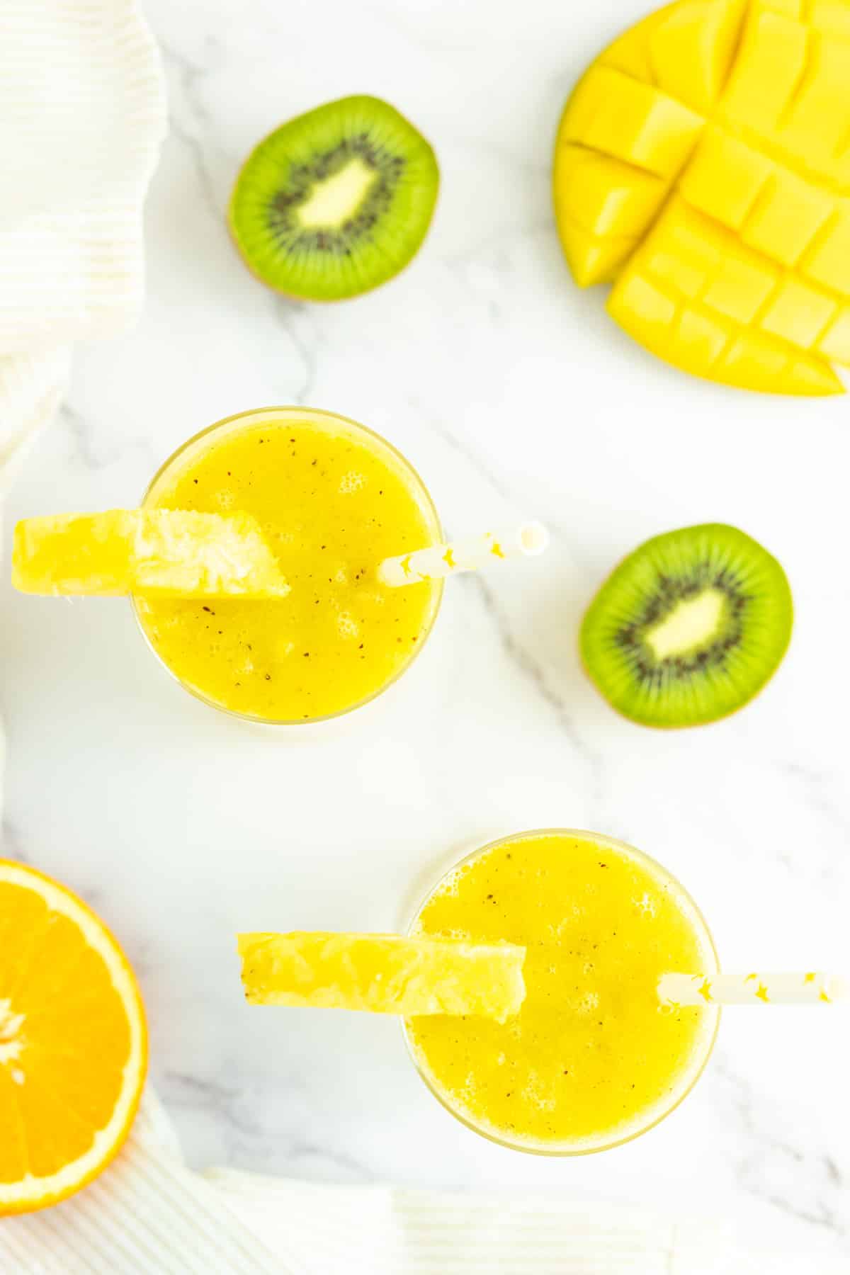 Two mango pineapple smoothies in a glasses.