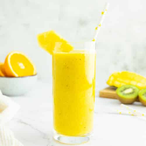 Mango pineapple smoothie in a glass with a straw.