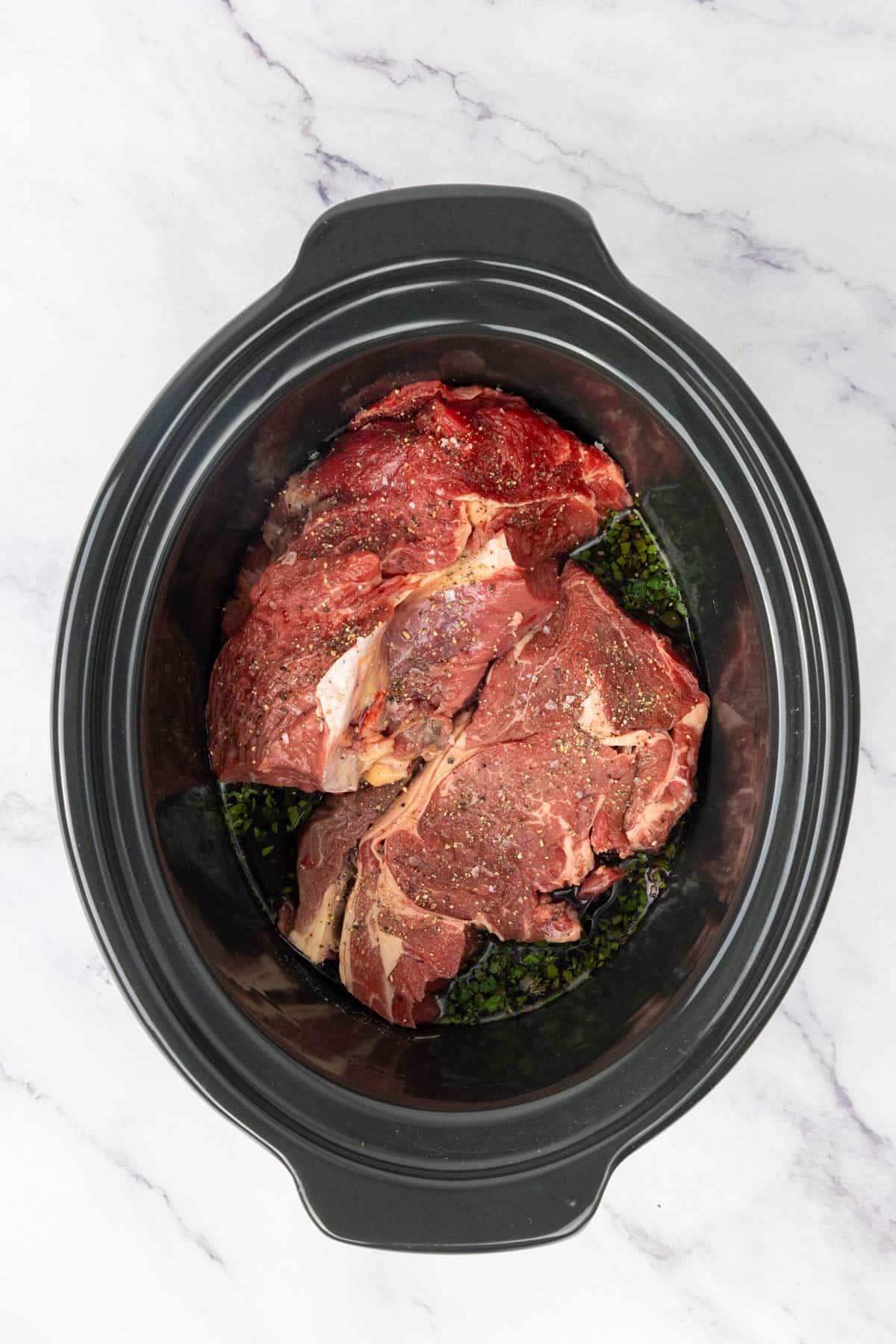 Beef, beef stock, red wine, parsley, thyme, salt and pepper in a slow cooker.