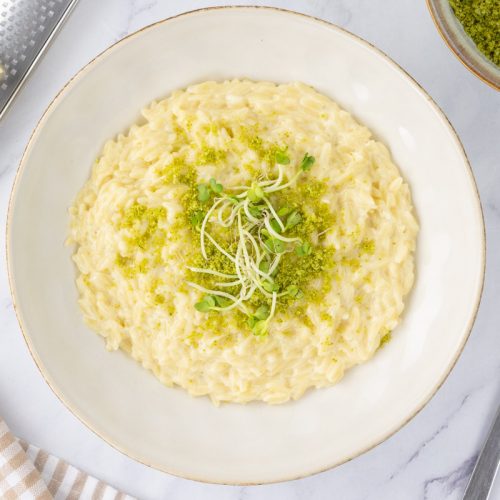 Truffle orzo in a bowl with micro herbs as garnish.