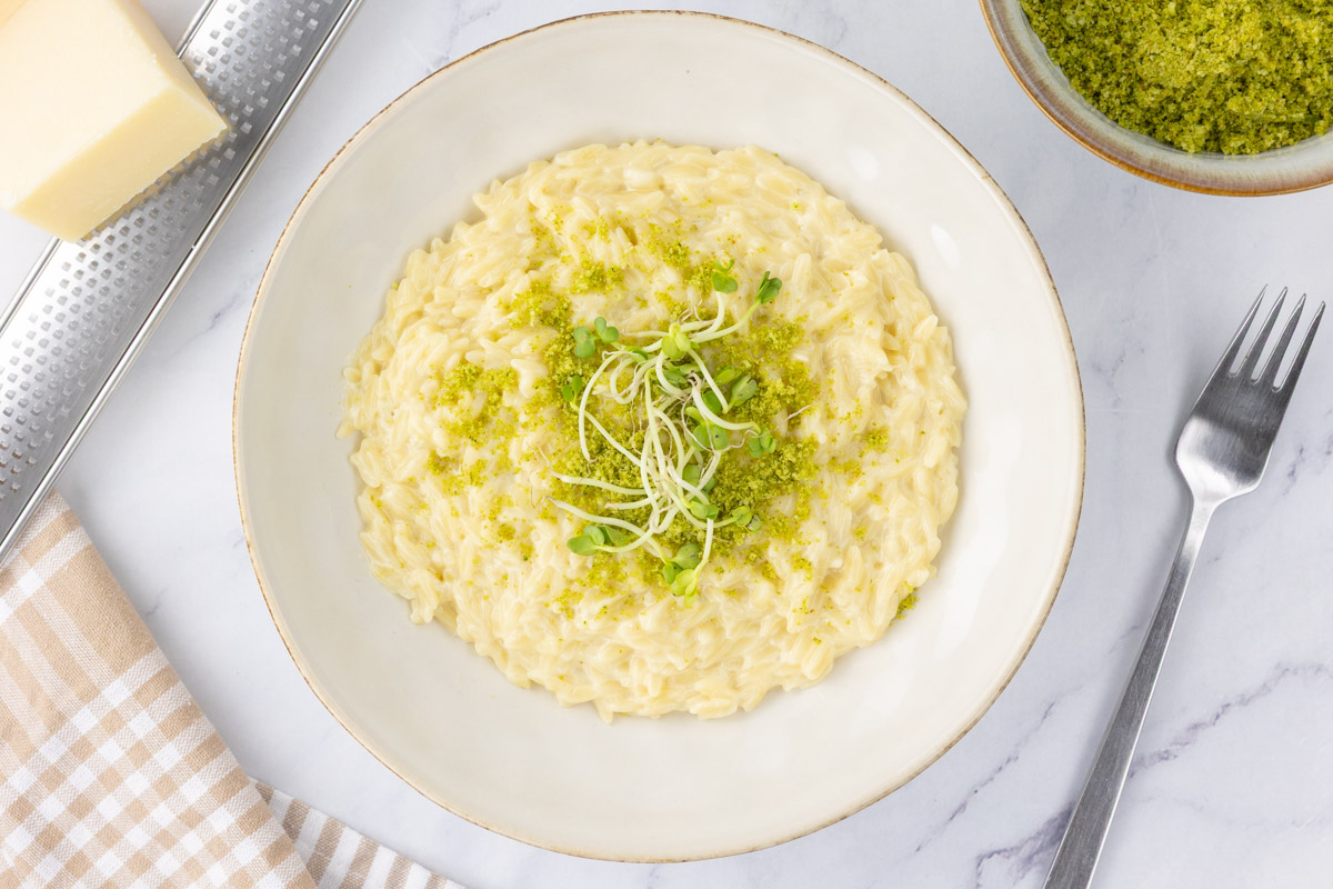 Truffle orzo in a bowl with micro herbs as garnish.